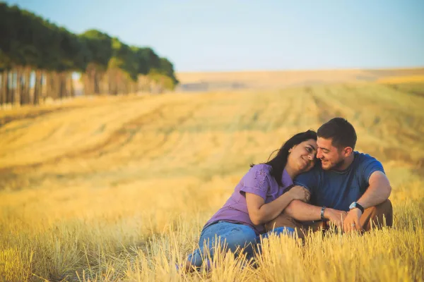 Couple amoureux assis dans un champ doré au coucher du soleil