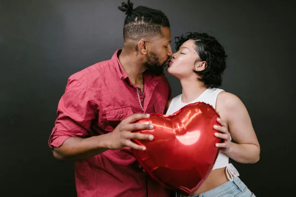 Couple amoureux s’embrassant avec un ballon cœur rouge