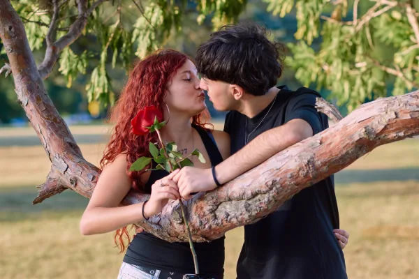 Jeune couple romantique avec une rose rouge dans un parc