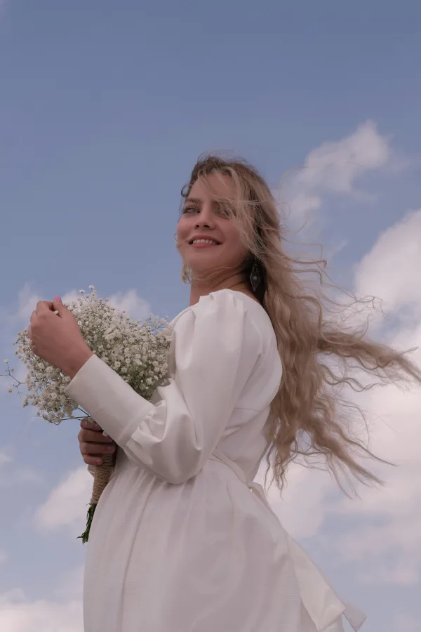 Jeune femme en robe blanche tenant un bouquet de fleurs