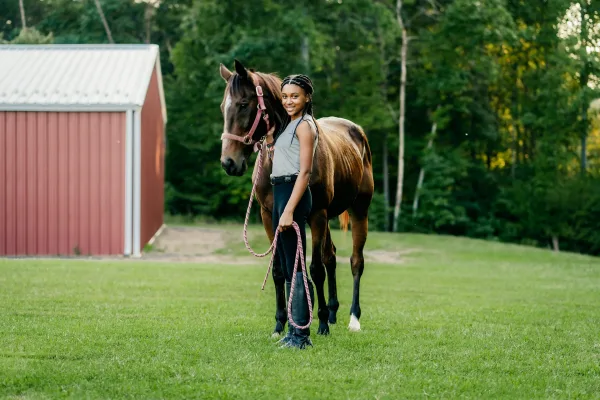 Jeune cavalière aux côtés de son cheval dans un cadre naturel
