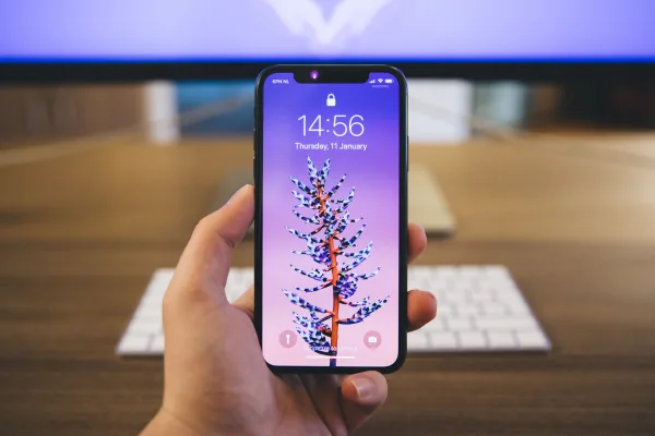 Smartphone moderne tenu en main sur un bureau de travail
