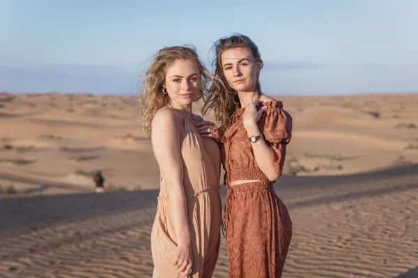Deux jeunes femmes posant dans les dunes du désert au coucher du soleil