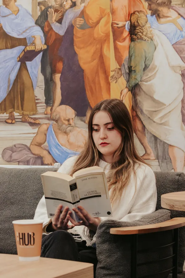 Jeune femme lisant un livre dans un café au décor artistique