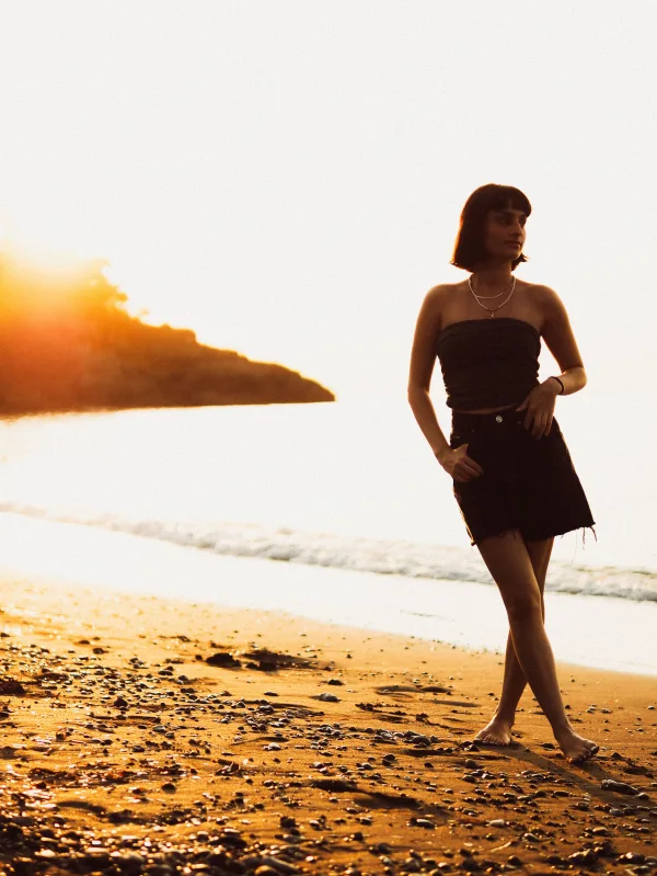 Jeune femme marchant sur la plage au coucher du soleil