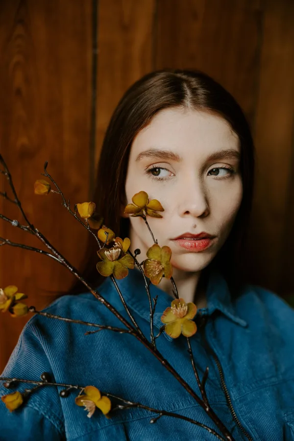Portrait artistique d'une jeune femme avec des fleurs sur fond en bois