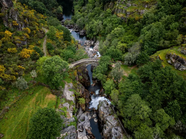 Vue aérienne d'un pont en pierre au cœur d'une vallée verdoyante