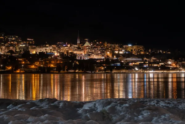 Ville illuminée au bord d'un lac en hiver – panorama nocturne