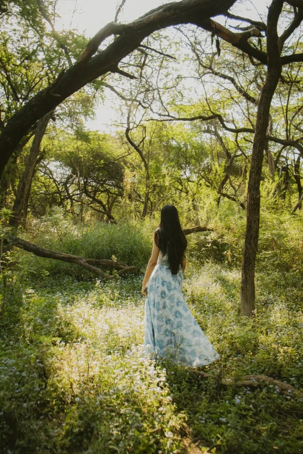 Femme en robe fleurie dans une forêt baignée de lumière