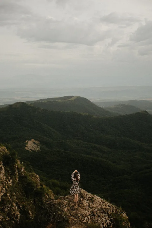 Femme contemplant un paysage montagneux – Vue panoramique sur des collines verdoyantes