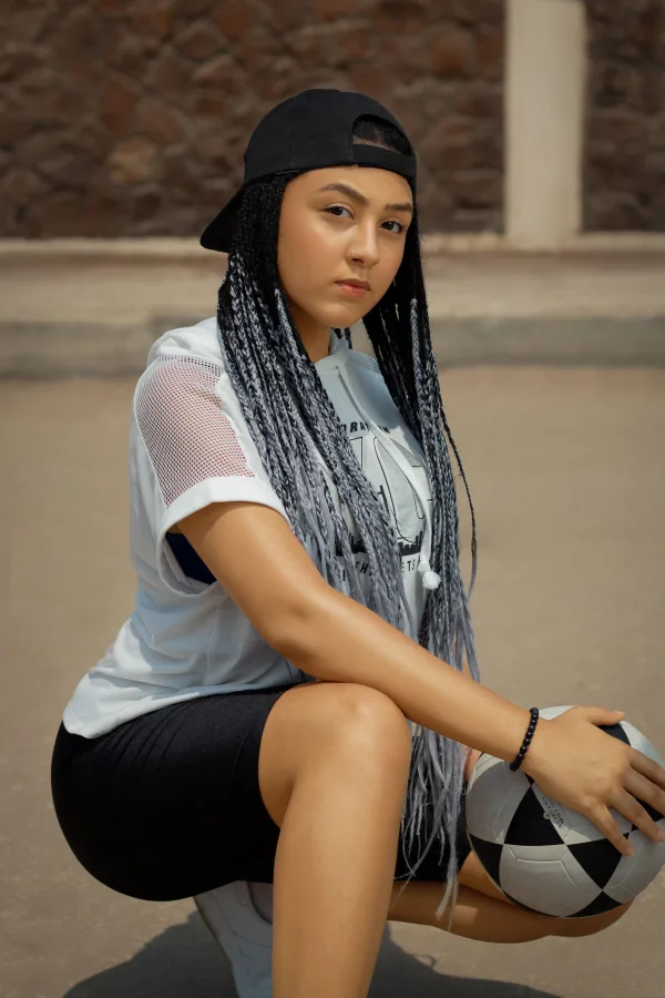 Jeune femme sportive tenant un ballon de football en tenue urbaine