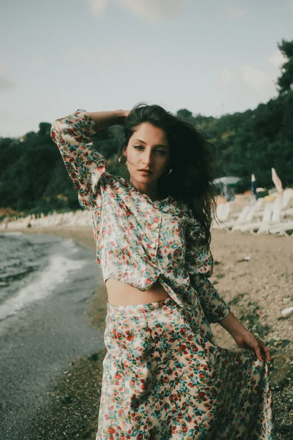 Portrait lifestyle d’une jeune femme en robe fleurie sur une plage