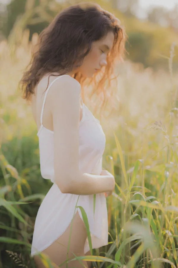 Jeune femme en robe blanche dans un champ au coucher du soleil
