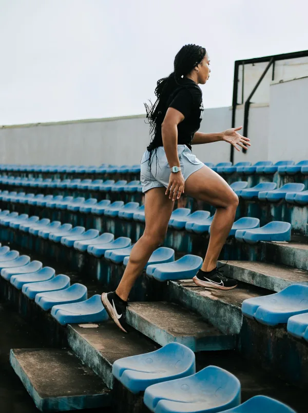 Athlète féminine courant dans les gradins d’un stade – entraînement cardio intensif