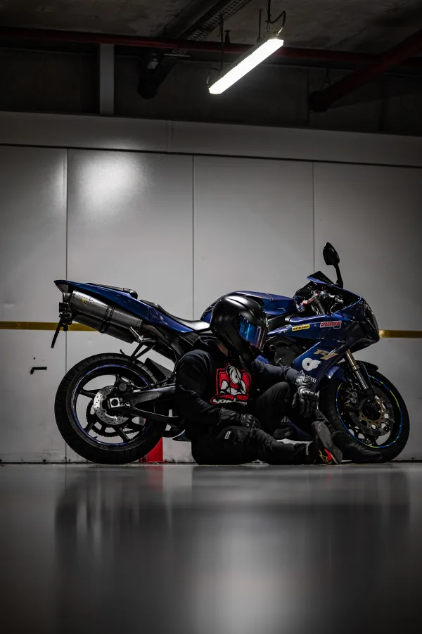 Motard assis à côté d’une moto sportive dans un parking souterrain