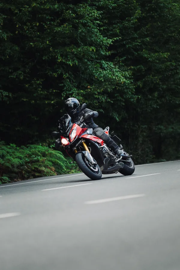 Motard sportif prenant un virage sur une route forestière