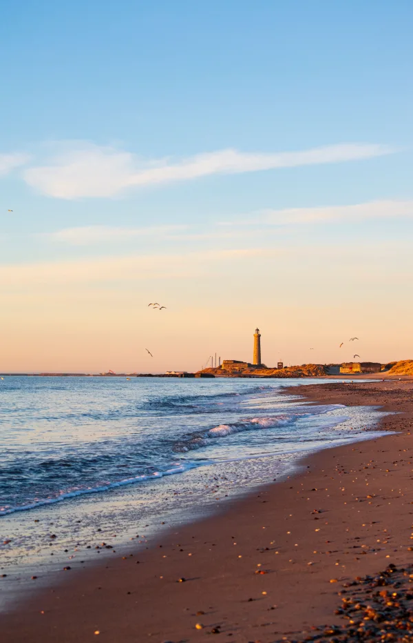 Plage paisible au coucher du soleil avec phare en bord de mer