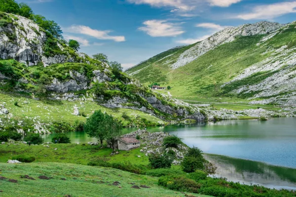Lac de montagne entouré de collines verdoyantes et de falaises rocheuses