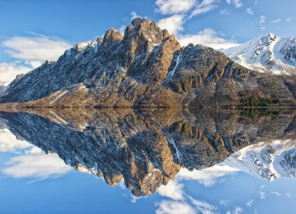 Montagnes enneigées se reflétant parfaitement dans un lac paisible