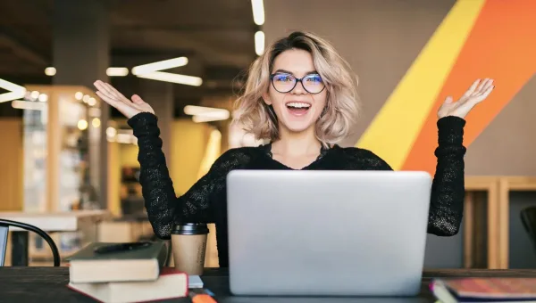 Jeune entrepreneuse célébrant sa réussite devant son ordinateur portable