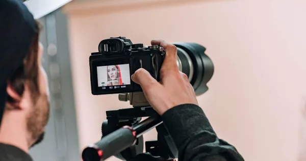 Vidéaste filmant une scène avec un appareil photo hybride pour la création de contenu