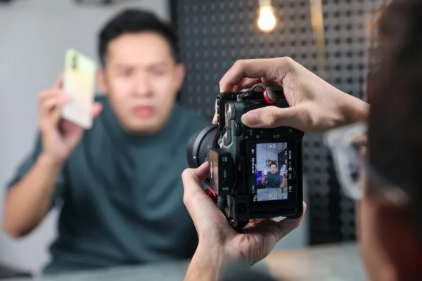 Créateur de contenu présentant un smartphone devant une caméra professionnelle