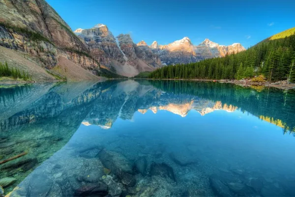 Lac de montagne cristallin avec reflet parfait des sommets enneigés