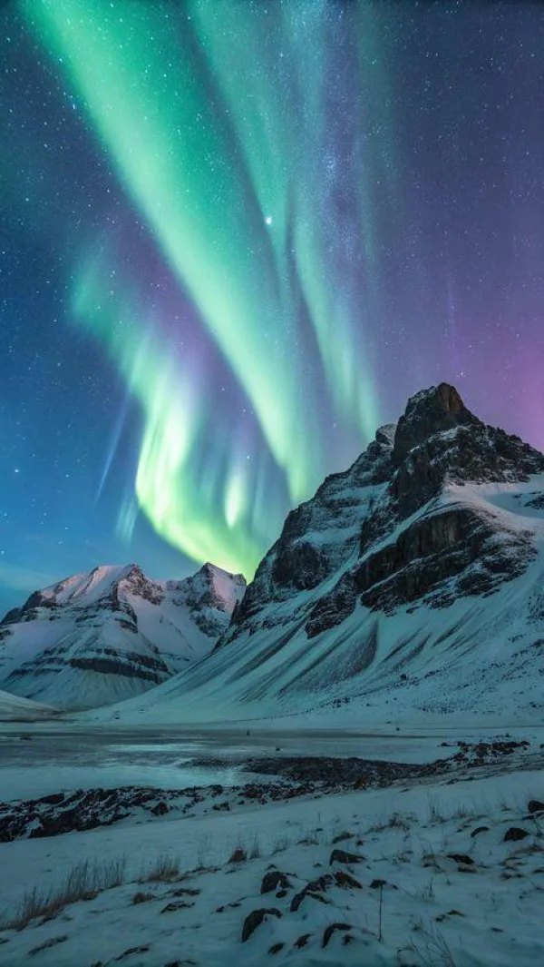 Aurore boréale au-dessus de montagnes enneigées sous un ciel étoilé