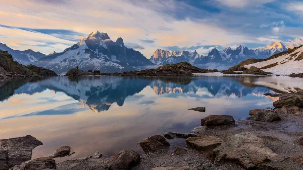 Lac de montagne reflétant des sommets enneigés au coucher du soleil