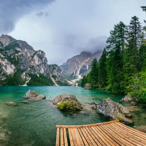 Lac de montagne émeraude entouré de falaises et de forêt de conifères
