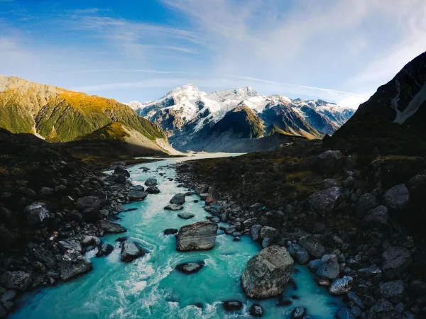 Rivière glaciaire turquoise traversant une vallée de montagnes enneigées