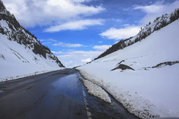 Route de montagne enneigée traversant un col alpin sous un ciel bleu