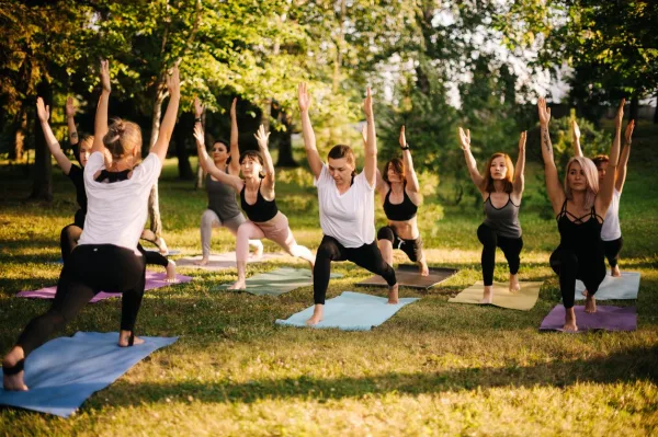 Cours de yoga en groupe dans un parc au coucher du soleil