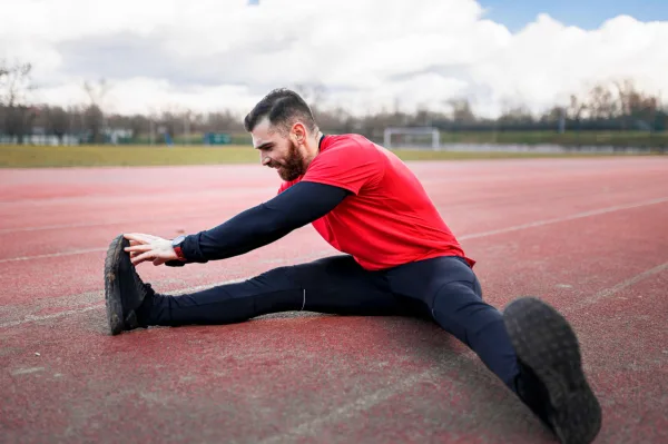 Athlète effectuant des étirements sur une piste d'athlétisme avant l'entraînement