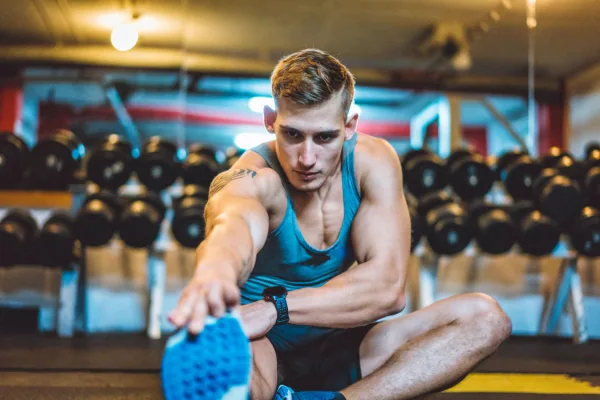 Homme s'étirant dans une salle de sport avant une séance de musculation