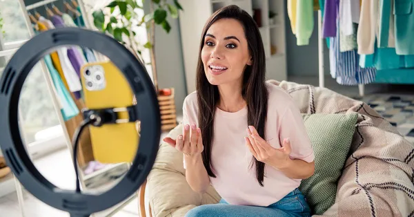 Influenceuse créant du contenu vidéo avec un smartphone et un ring light