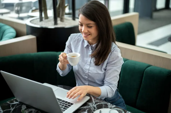 Jeune femme en télétravail dans un café avec un ordinateur portable et une tasse de café