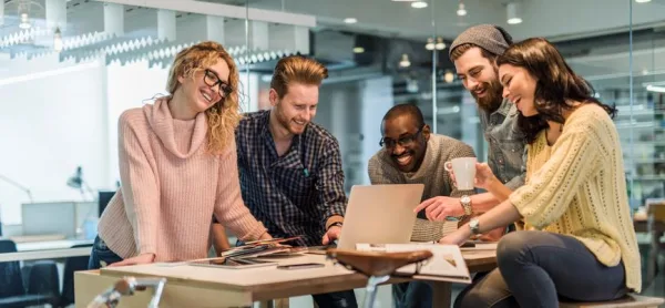 Équipe de freelances en réunion collaborative autour d’un ordinateur portable dans un espace de coworking