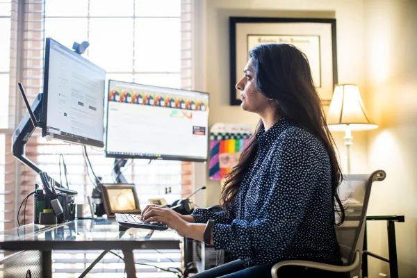 Professionnelle en télétravail utilisant un double écran dans un bureau à domicile moderne