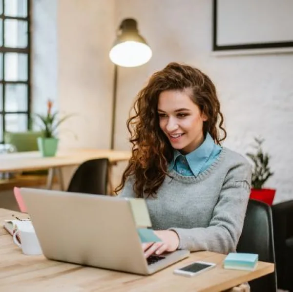 Jeune femme souriante travaillant sur un ordinateur portable dans un bureau moderne