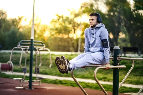 Jeune homme s'entraînant sur des barres parallèles dans un parc de fitness