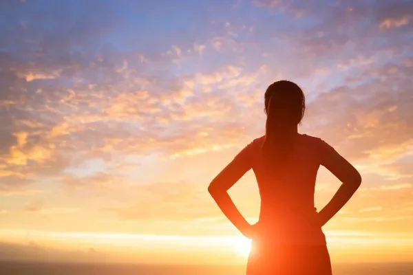 Silhouette de femme face au lever du soleil, symbole de confiance en soi, de force intérieure et d'avenir prometteur