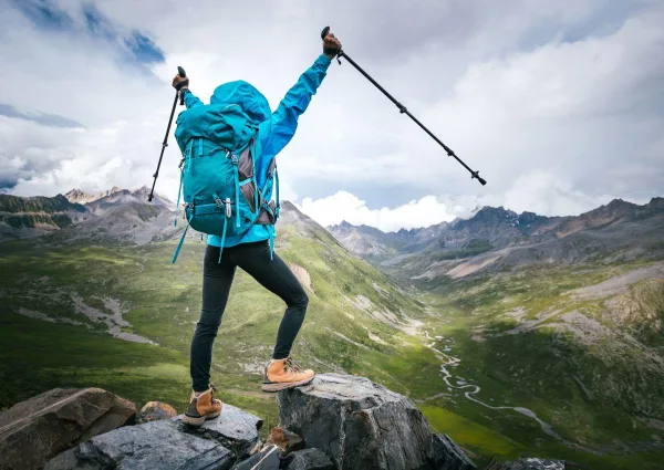 Randonneur levant les bras au sommet d'une montagne, symbole de victoire, de confiance en soi et de dépassement de soi