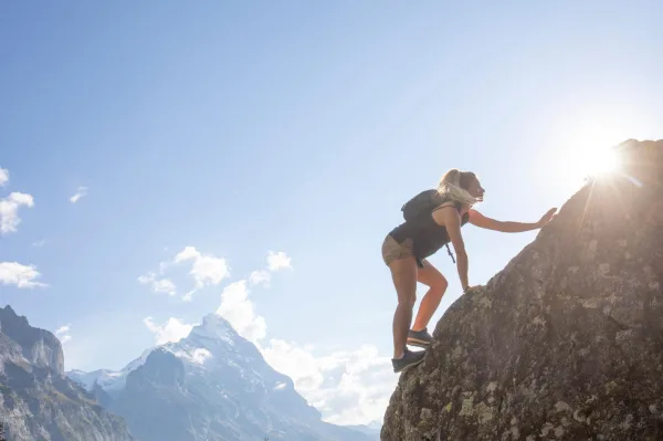 Femme escaladant une montagne, symbole de persévérance, de confiance en soi et de dépassement de soi