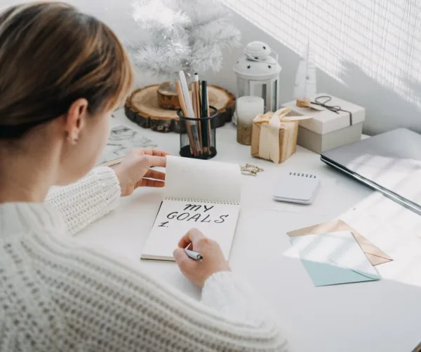 Personne écrivant ses objectifs dans un carnet, symbole de planification, de motivation et de réussite personnelle