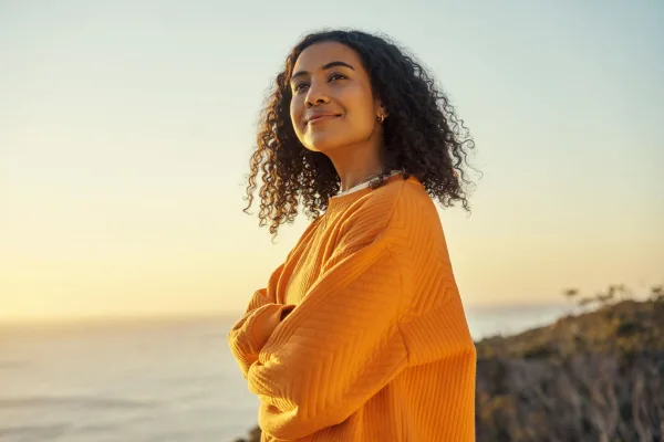 Jeune femme souriante face à l'horizon, symbole de confiance en soi, de sérénité et d'épanouissement personnel