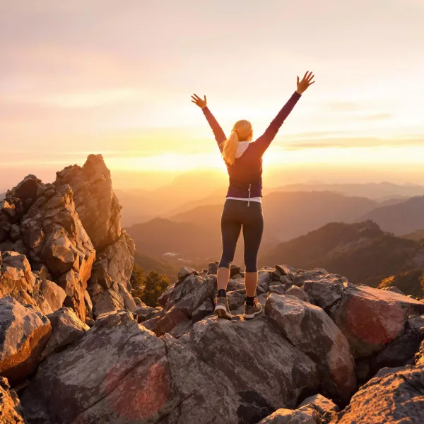 Femme célébrant sa réussite au sommet d'une montagne au lever du soleil