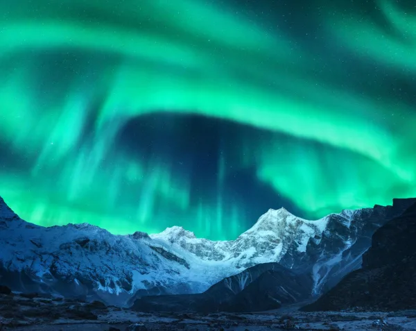 Aurores boréales au-dessus de montagnes enneigées sous un ciel étoilé