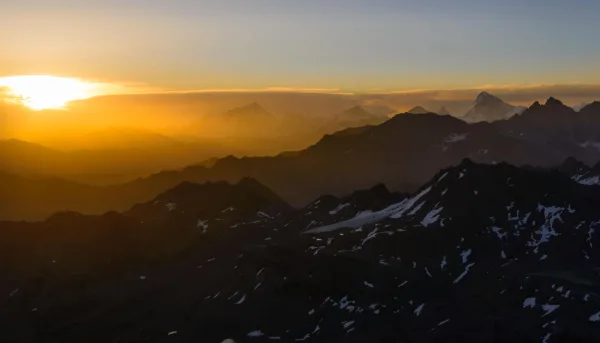 Coucher de soleil sur une majestueuse chaîne de montagnes aux sommets enneigés