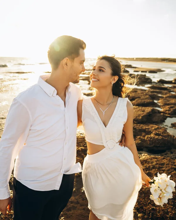 Couple romantique marchant sur une plage au coucher du soleil